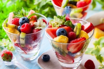 Brazilian tropical fruit salad with fresh fruits and mint leaves in glass cups.