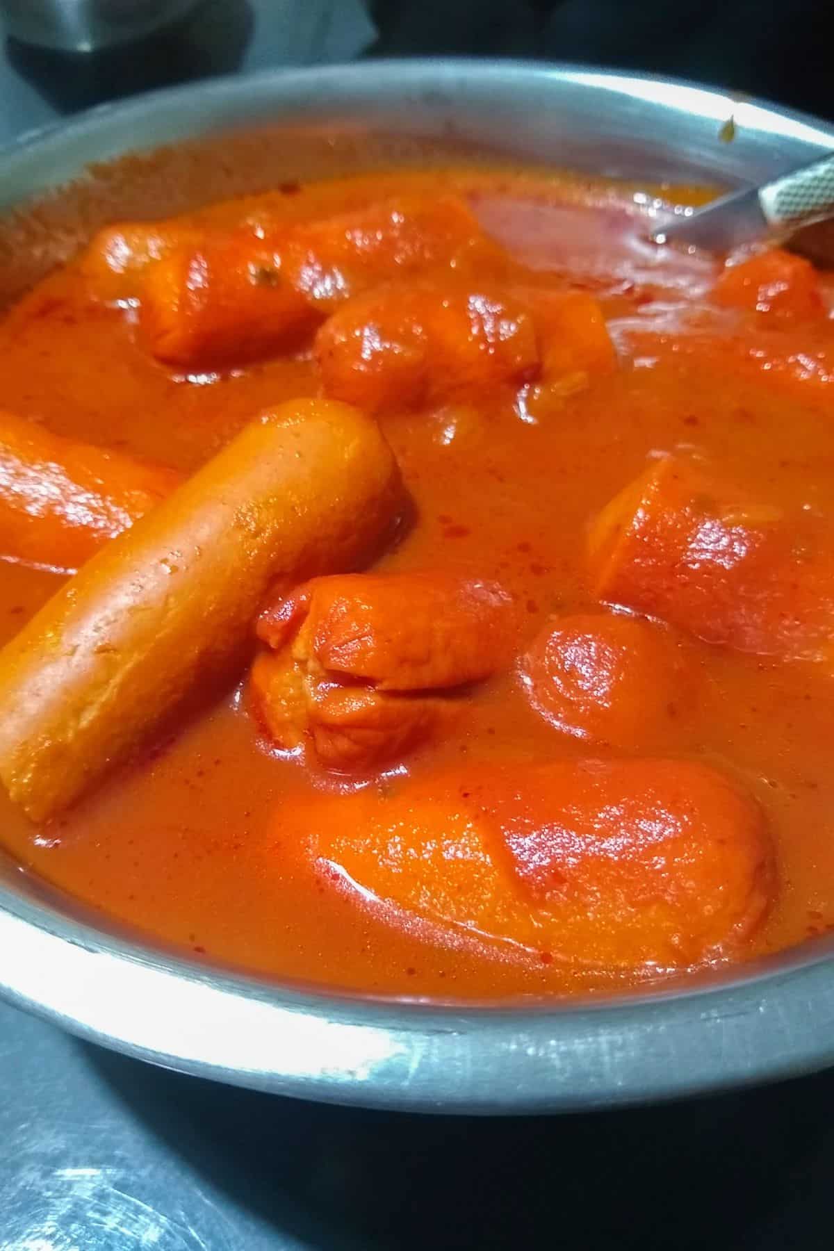 A pan with sausage links in tomato sauce.