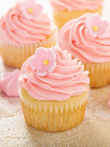 Passion fruit cupcakes filled with mousse and topped with a pink frosting.