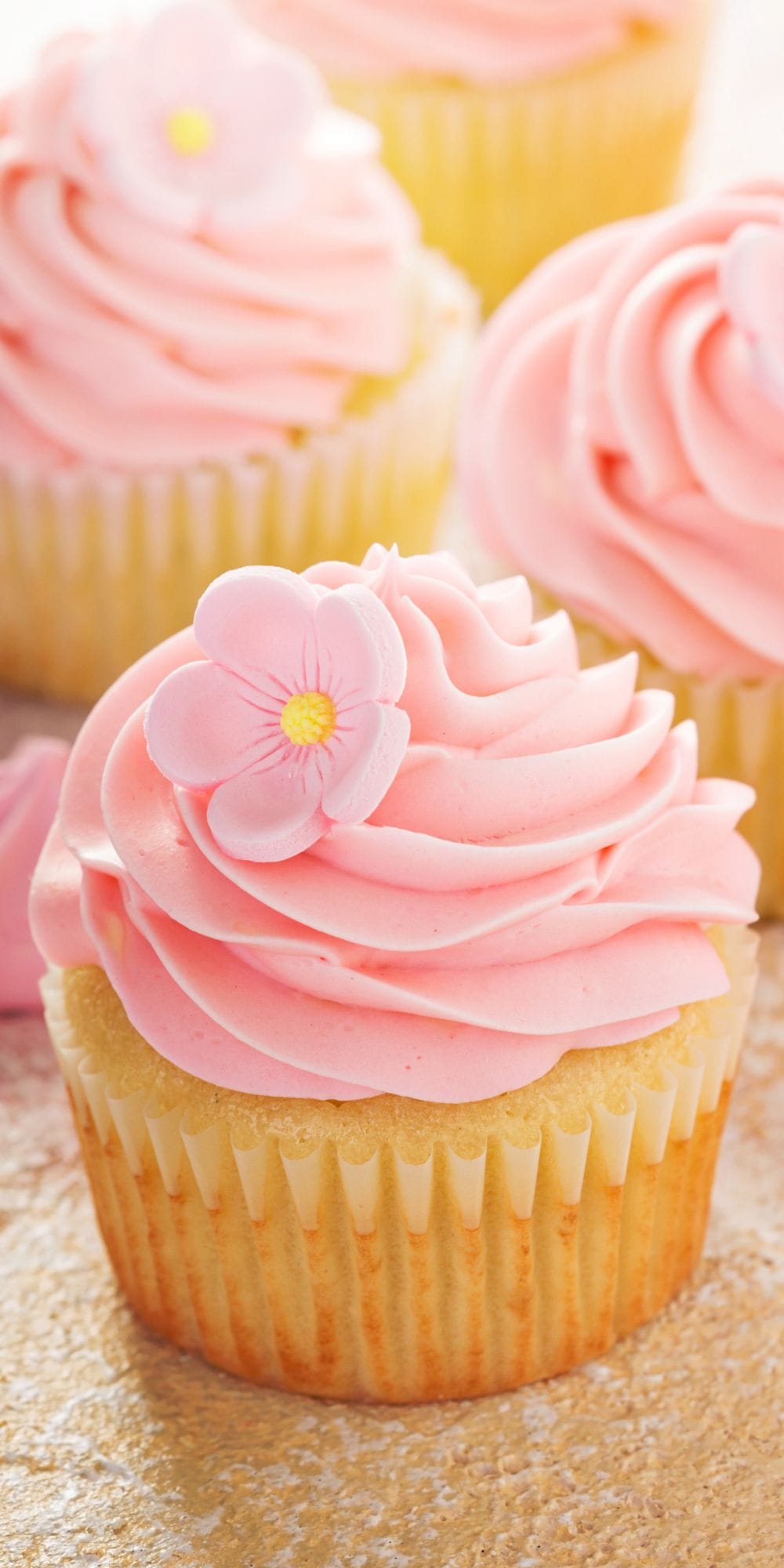 Several passion fruit cupcakes filled with passion fruit mousse and topped with pink buttercream frosting.