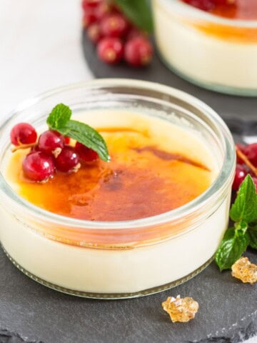 Ramekins with coconut creme brulee garnished with fresh currants and mint leaves.
