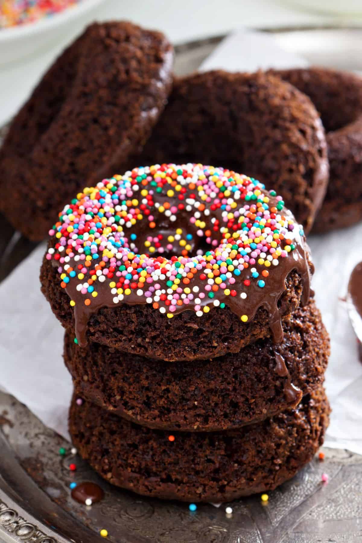 A pile of protein donuts topped with melted chocolate and sprinkles.