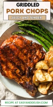 Close up image of cooked pork chops on blackstone with sauteed asparagus and crispy potatoes.