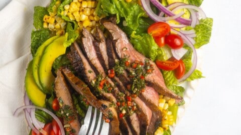 A forkful of flank steak salad taken from a platter.