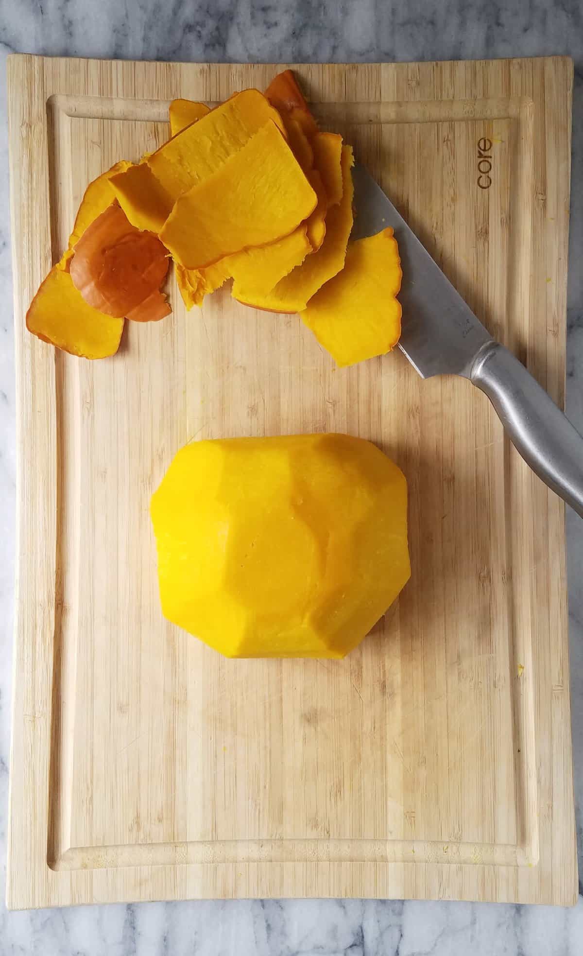 A pumpkin peeled on a cutting board.