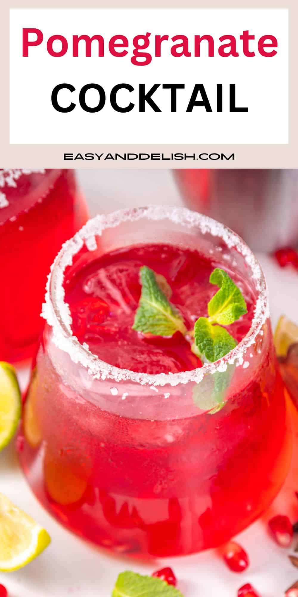 A glass of vodka pomegranate cocktail with a sugary rim and garnishes on top and on the sides. 