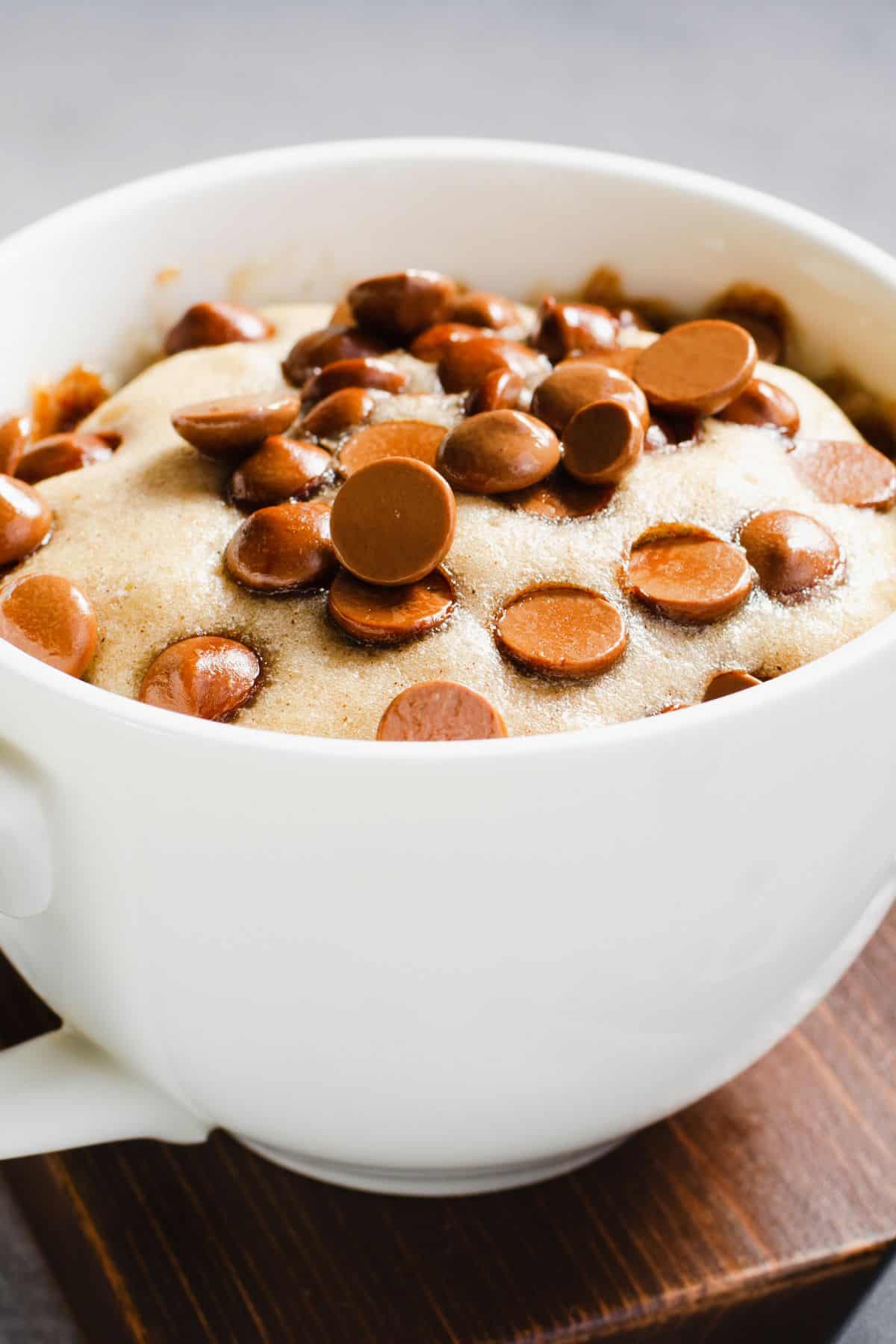 Chocolate chip protein mug cake with cottage cheese on a wood surface.