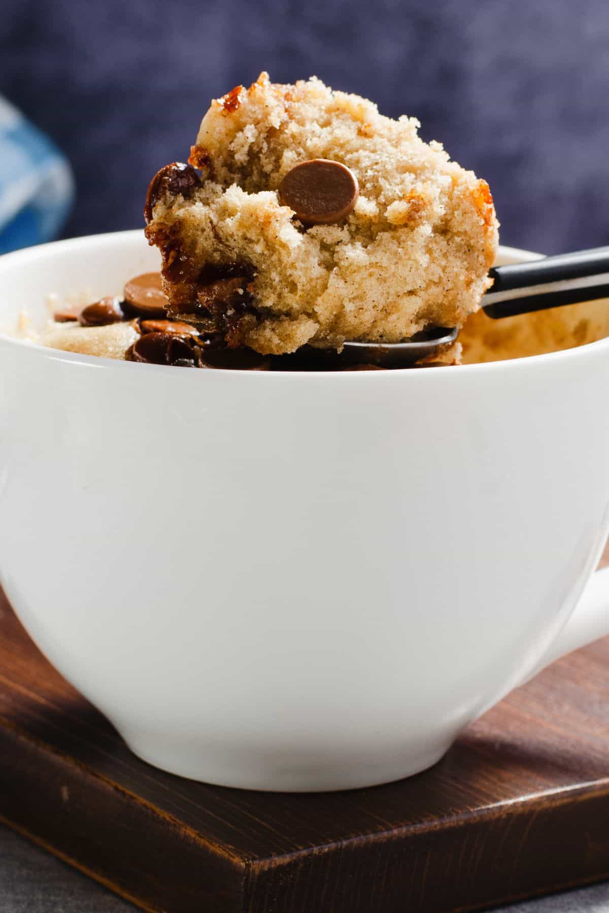 A spoonful of cake held over a mug. 